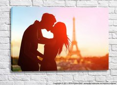 Un cuplu de îndrăgostiți se sărută pe fundalul Turnului Eiffel