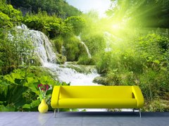 Водопад на фоне зеленых растений и ярких солнечных лучей