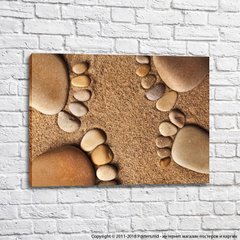 Камни выложенные в виде ступней на фоне песка
