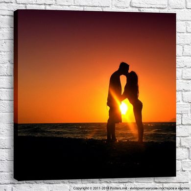 Cuplu îndrăgostit îmbrățișând și sărutându-se pe plajă, apus de soare